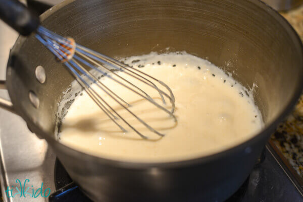 Cooking flour and butter together in a saucepan, stirring with a whisk, to make the roux.