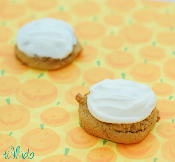 Pumpkin Cookies with cream cheese icing on a pumpkin print background.