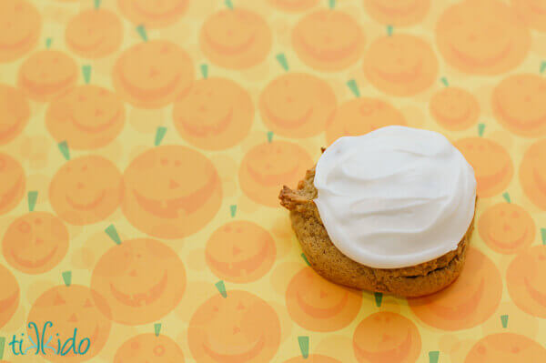Soft Pumpkin Cookie with cream cheese frosting on a pumpkin patterned background.