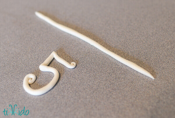 White gum paste rolled into a long rope and shaped into the number five.
