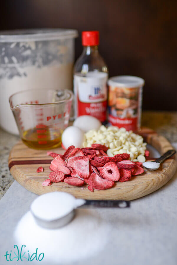 Ingredients for White chocolate strawberry biscotti cookies on a wooden cutting board.