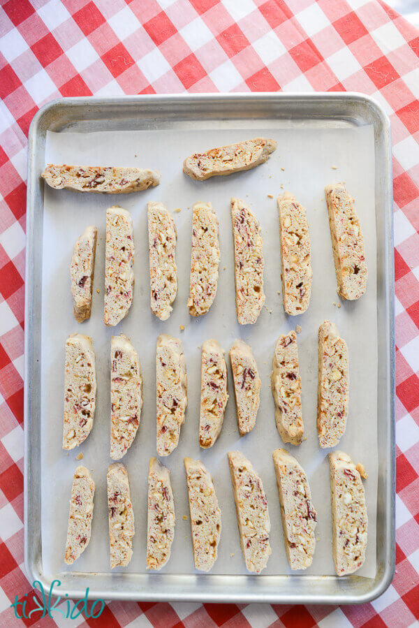 White chocolate strawberry biscotti arranged on a parchment lined baking sheet, ready for their second bake.