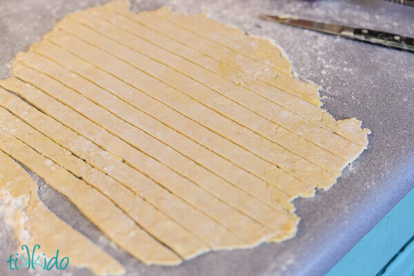 Pie crust being cut into strips for a lattice crust rhubarb custard pie.