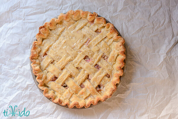 Lattice crust rhubarb custard pie on a white paper background.