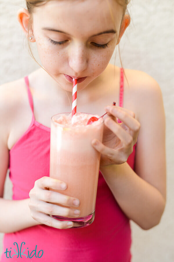 Little girl in a pink tank top sipping a Shirley Temple Ice Cream Float.