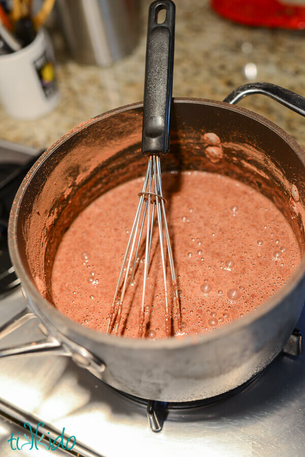 Homemade, dairy free fudgesicle mixture being cooked in a saucepan with a whisk.