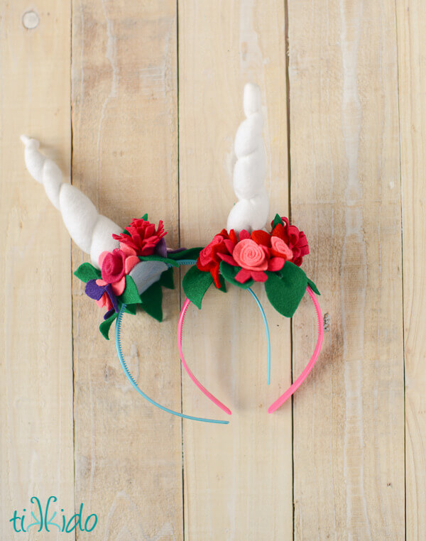 two felt unicorn horn headbands with felt flowers on a whitewashed wood background.