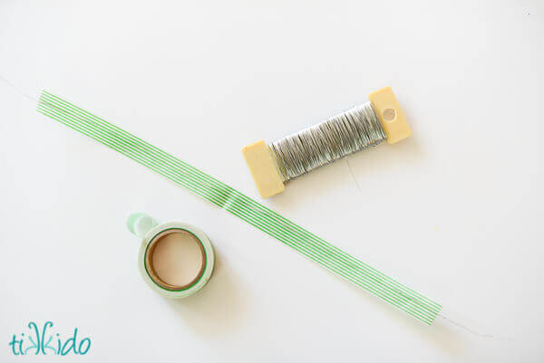Green and white striped washi tape and silver floral wire on a white background.