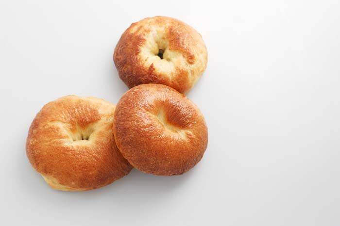 Three homemade bagels on a white surface