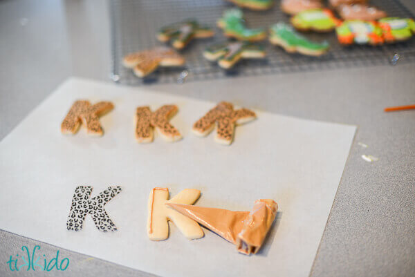 K shaped Sugar cookies being decorated with chocolate.