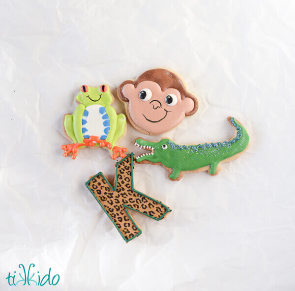 K shaped sugar cookie decorated with chocolate surrounded by jungle cookies decorated with royal icing.