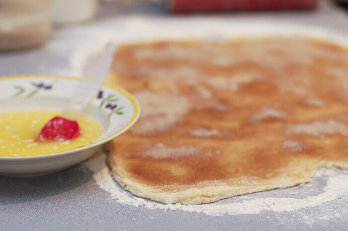 Cinnamon roll dough rolled out and sprinkled with cinnamon sugar.