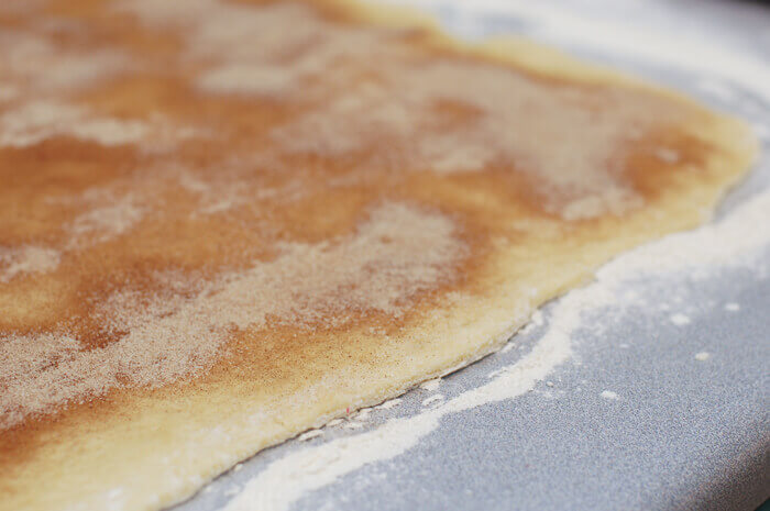 Cinnamon roll dough rolled out and sprinkled with cinnamon sugar.