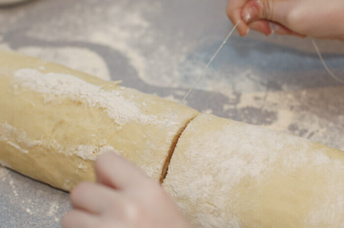 Cutting cinnamon roll dough using a thread.