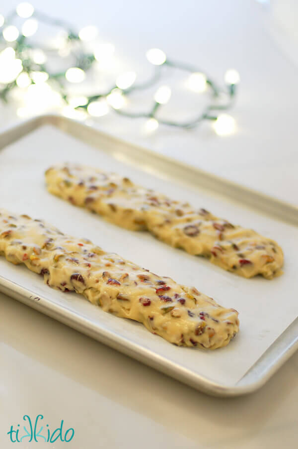 Cranberry Pistachio Biscotti dough formed into two logs, ready to bake on a parchment lined baking sheet.