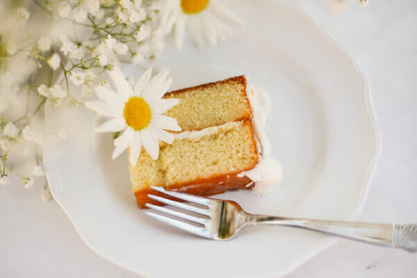 Slice of vanilla cake with apricot glaze and an amaretto cake soak on a white plate.