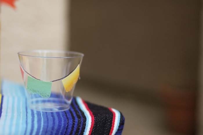 Miniature Mexican papel picado decorating plastic cups for a Day of the Dead celebration.