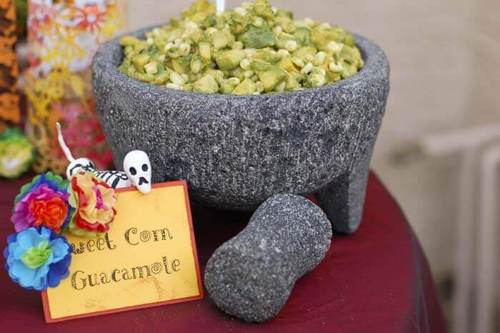 Chunky sweet corn guacamole in a large grey stone mortar and pestle.
