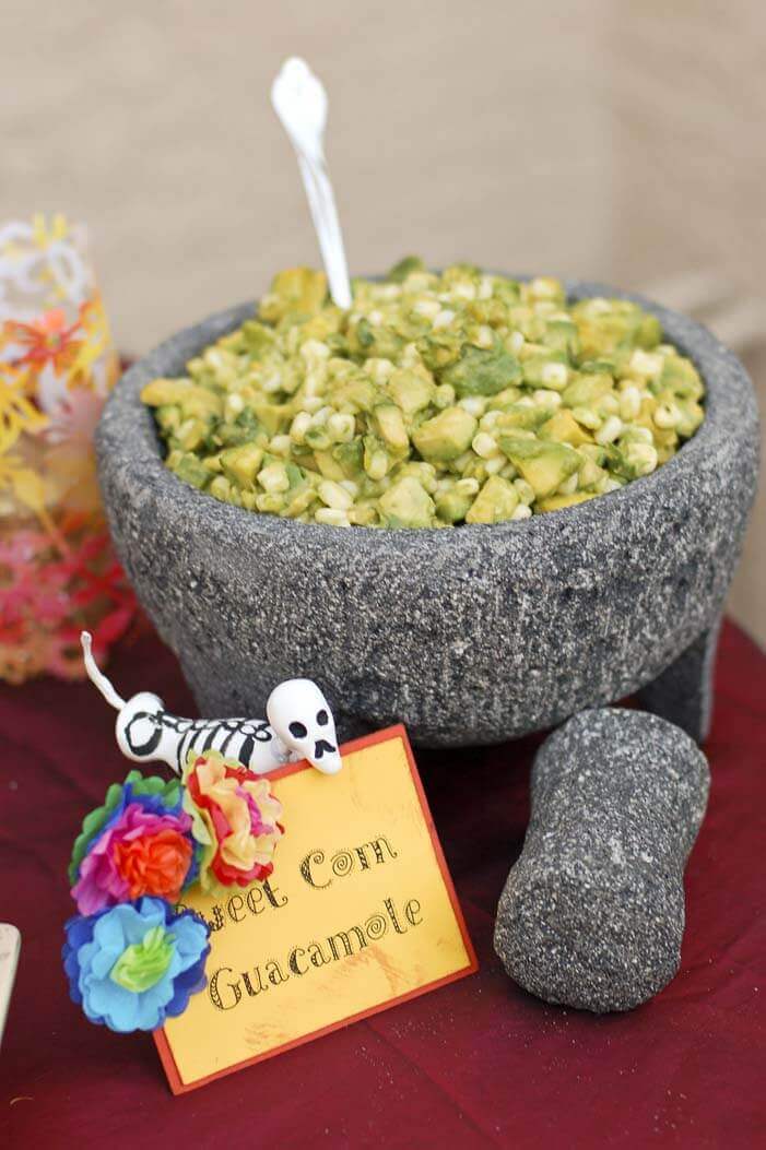 Chunky sweet corn guacamole in a large grey stone mortar and pestle.