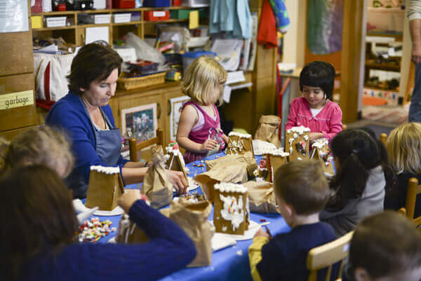 Preschoolers decorating gingerbread houses.