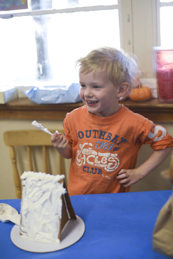 Little boy decorating a gingerbread house with royal icing.