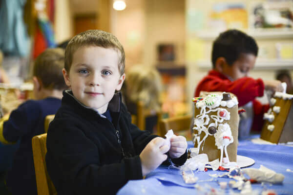 Preschool aged boy decorating a gingerbread house.