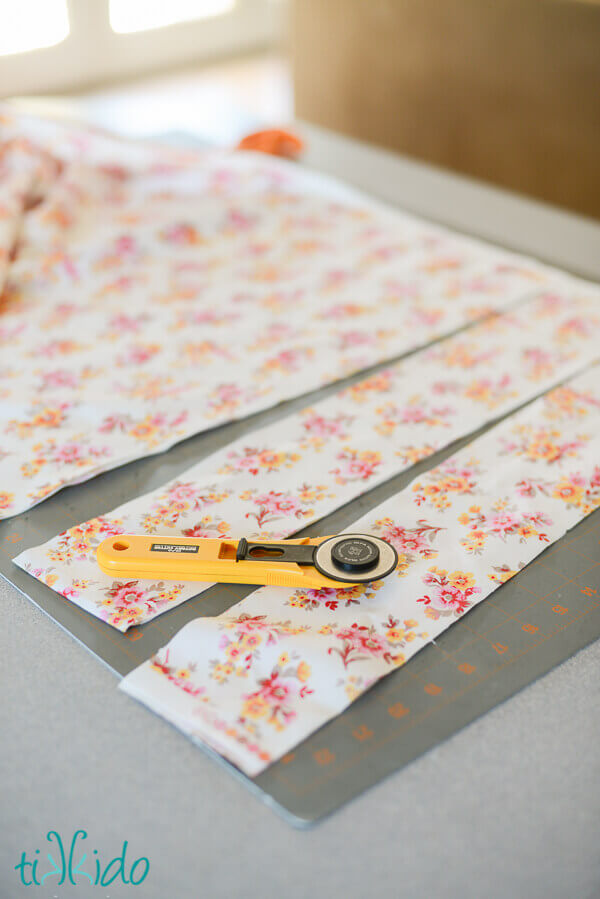Fabric being cut into strips with a rotary cutter on a self healing cutting mat.