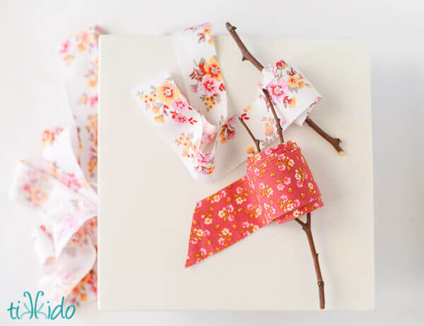 Two spools of DIY fabric ribbon wound around branches on a white background.