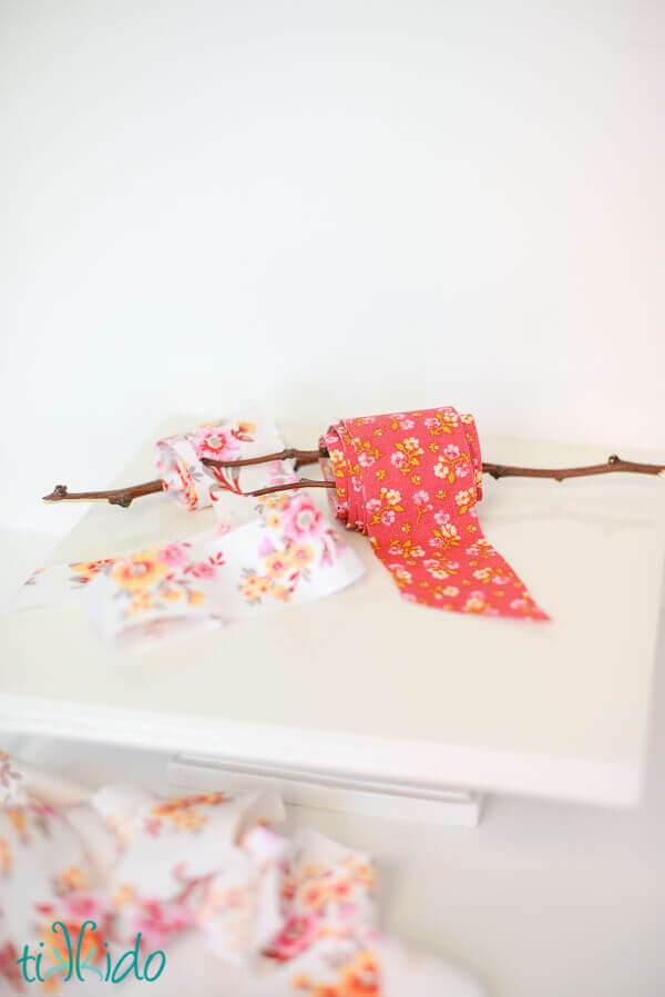 Two spools of DIY fabric ribbon wound around branches on a white background.