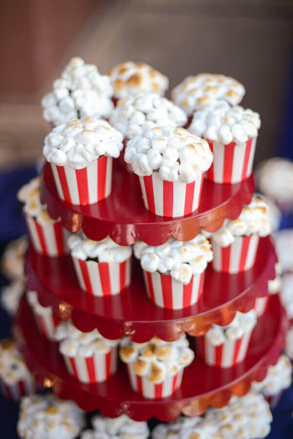 Three tiered red cake stand covered in popcorn cupcakes cupcakes baked in red and white striped baking cups.