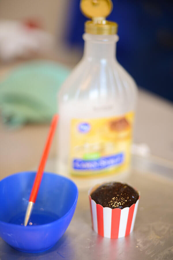 Chocolate cupcake baked in a red and white paper baking cup, brushed with clear corn syrup to make popcorn cupcakes.