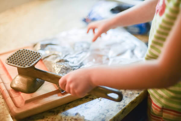 Little girl crushing oreos with a mallet to make edible dirt.