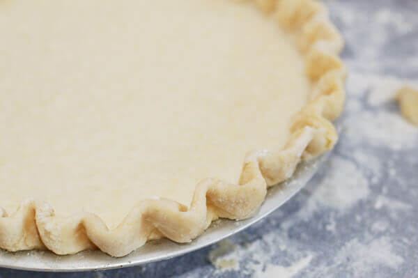 Unbaked pie crust in a pie tin on a countertop.