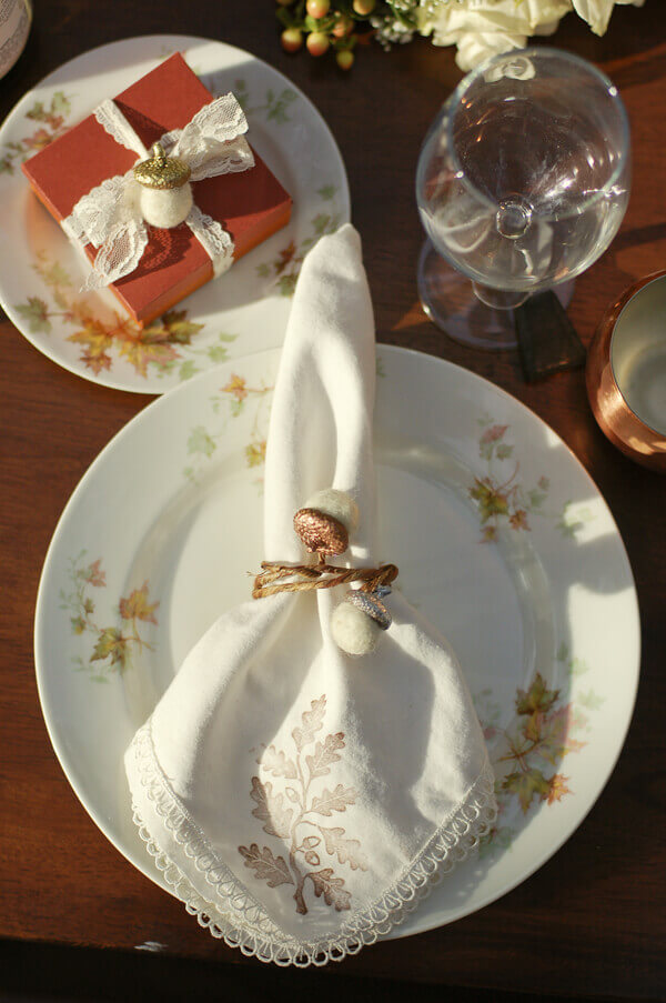 Felt acorns on a napkin ring and a favor box at a fall table setting.