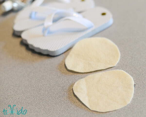 Close-up shot of female legs in white velour trousers and blue plush house  slippers made as shaggy hobbit feet. The girl is standing on the striped  gray and white carpet. Stock Photo |