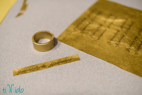 Gold tissue paper printed with the engraved words on the One Ring from Lord of the Rings and being glued to gold napkin rings.