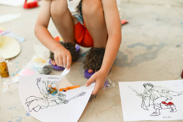Child making LOTR themed art while wearing hairy hobbit feet flip flops.