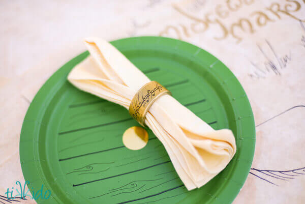 Lord of the Rings One Ring napkin rings for a hobbit party on a green paper plate that looks like a hobbit hole door.