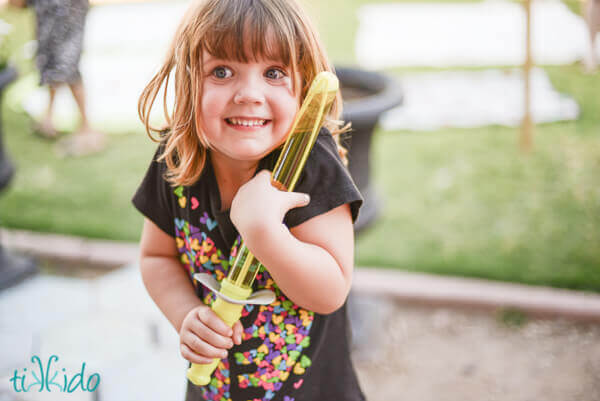 Little girl excitedly holding a bubble sword at the Hobbit birthday party.