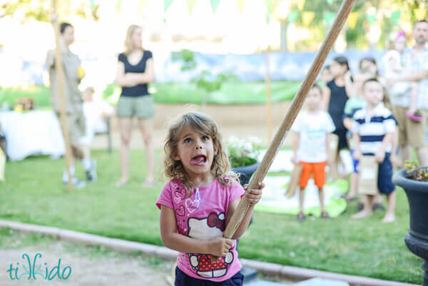 Little girl attempting to hit a dragon piñata at the Hobbit birthday party.