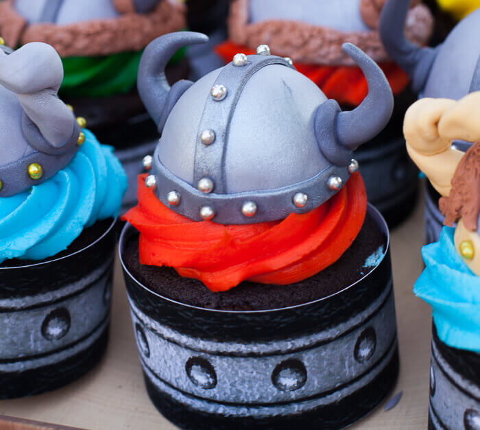 Gum paste viking helmet on a cupcake with red icing for a How to Train your Dragon Party.