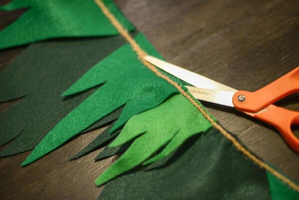 Orange scissors trimming away excess felt from Peter Pan inspired bunting.