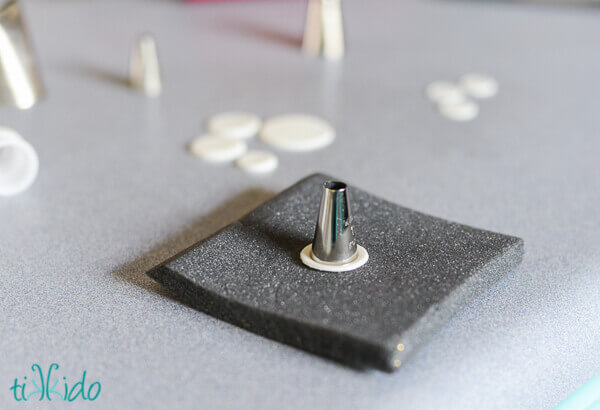 Foam and icing tips being used to make miniature gum paste plates for tea party cupcake toppers.