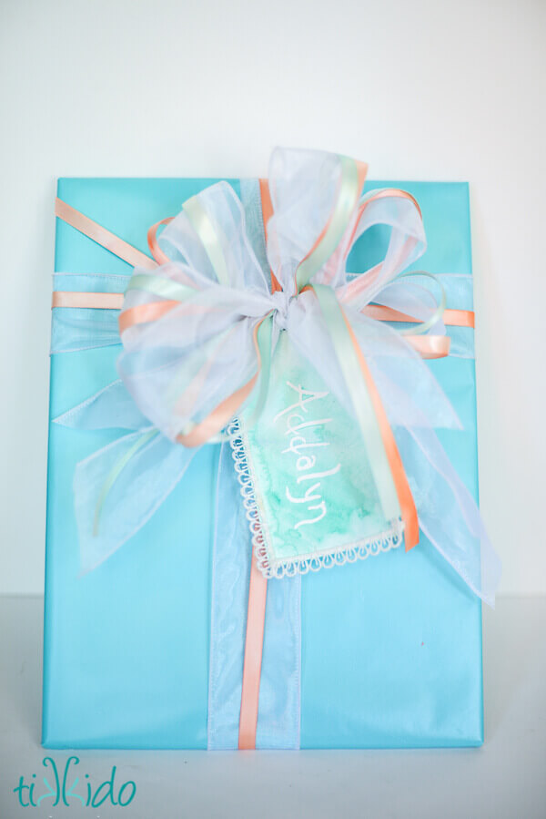Gift wrapped in turquoise paper and finished with a bow made from painted ribbon.