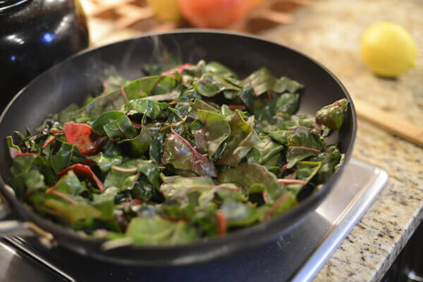 Swiss chard being sautéed for a quinoa bowl recipe.