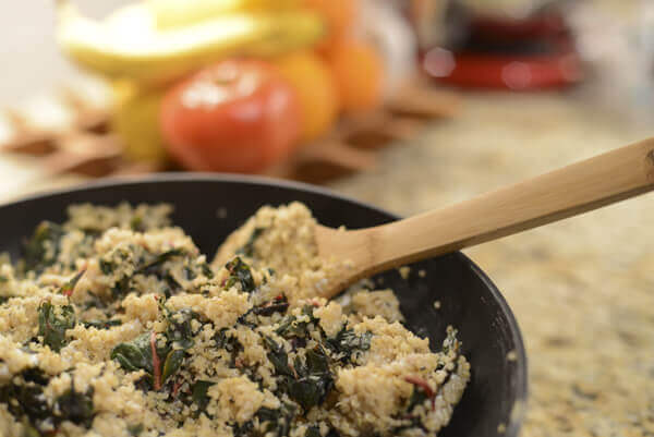 Quinoa bowl recipe with goat cheese and Swiss chard being made in a sauce pan.