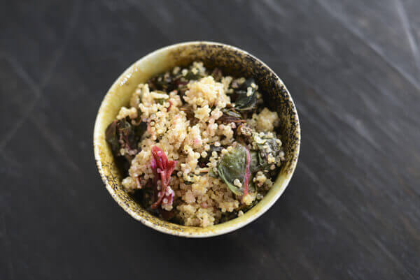 Quinoa, goat cheese, and Swiss chard Quinoa Bowl Recipe in a green pottery bowl.