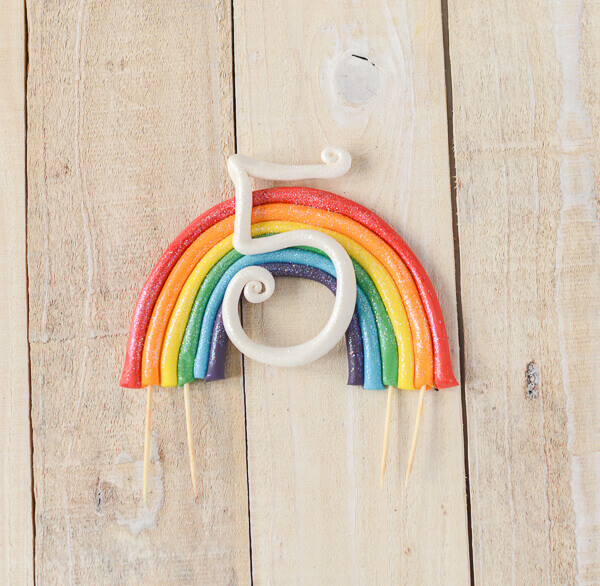 Gum Paste Rainbow Cake Topper on a wooden background.