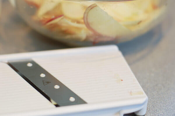 Apples being thinly sliced using a mandoline for Rose Apple Pie