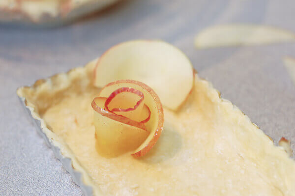 Thin slices of apples being shaped into roses for the rose apple pie.